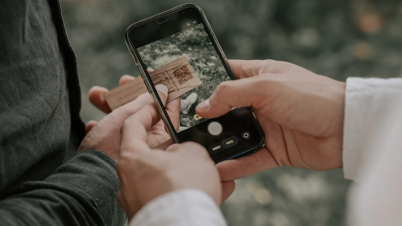 Ein Gast scannt den QR-Code des Holzmagneten mit dem Smartphone